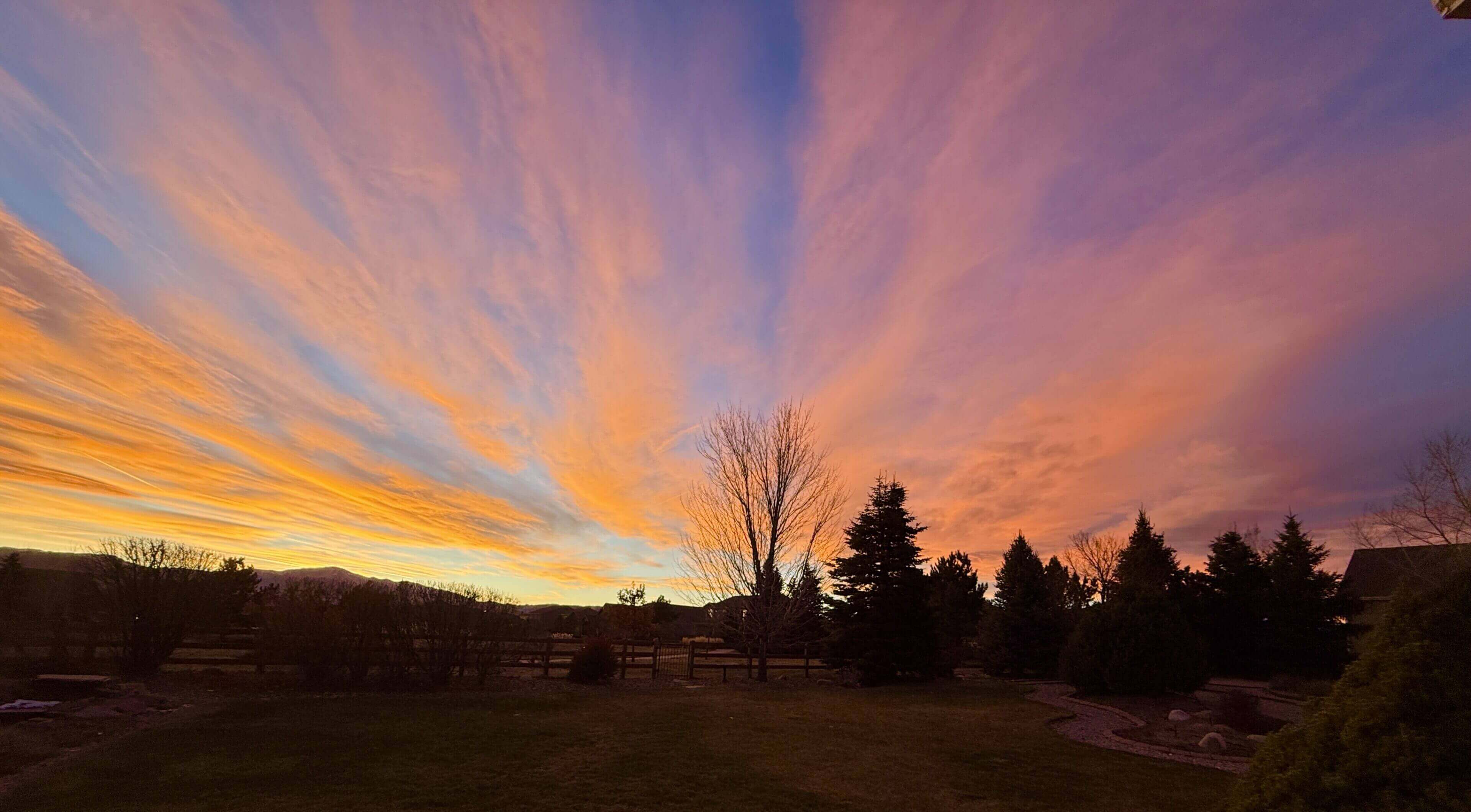 Colorful sunset sky over silhouetted trees.