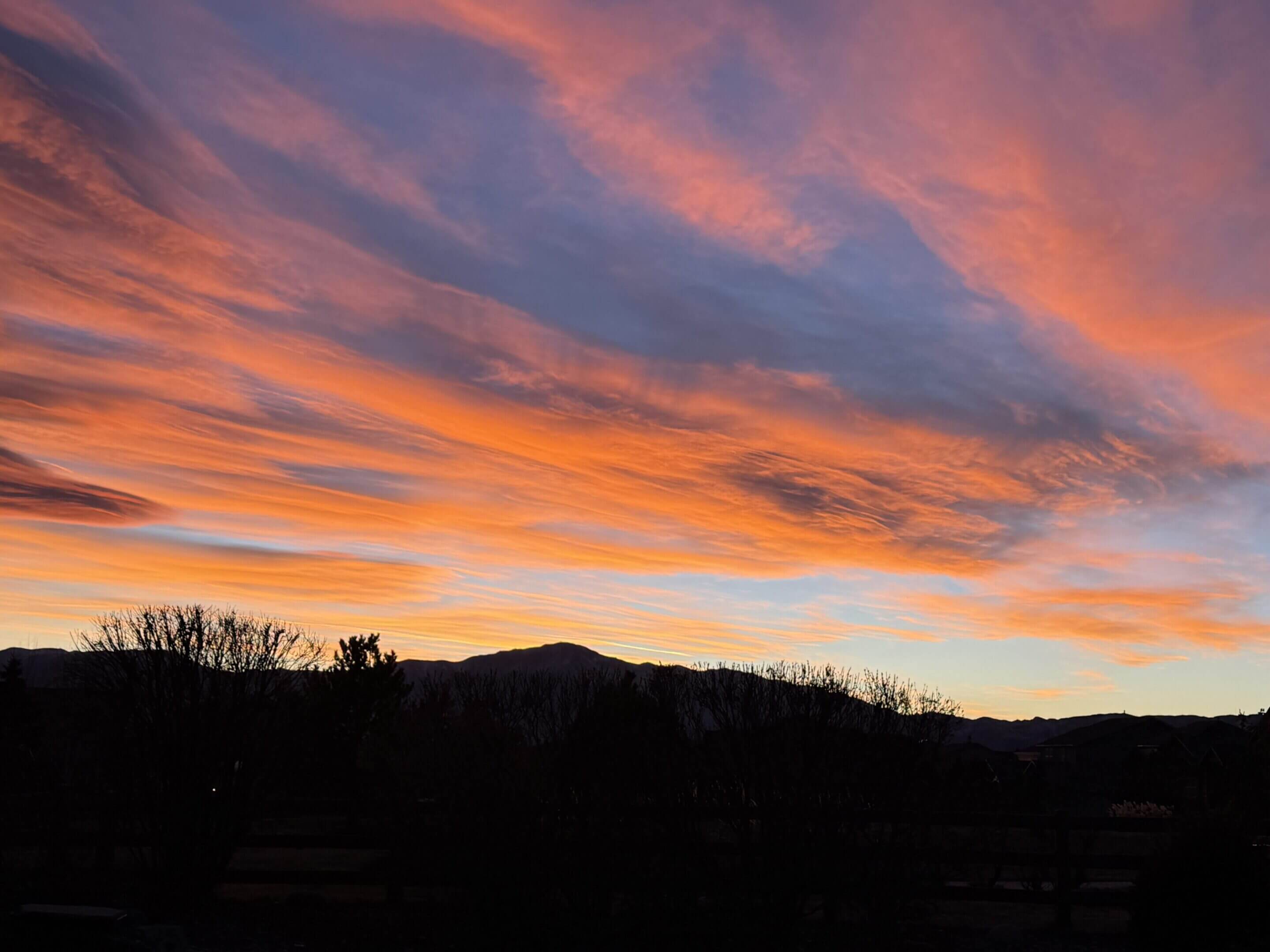 Vibrant sunset sky over silhouetted landscape.